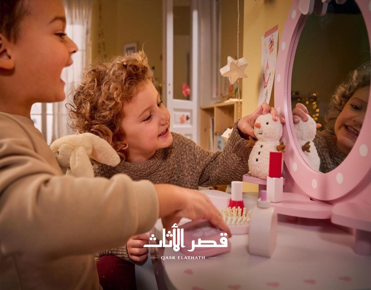 طفلان يستخدمان طاولة التجميل وأدوات اللعب الخشبية
