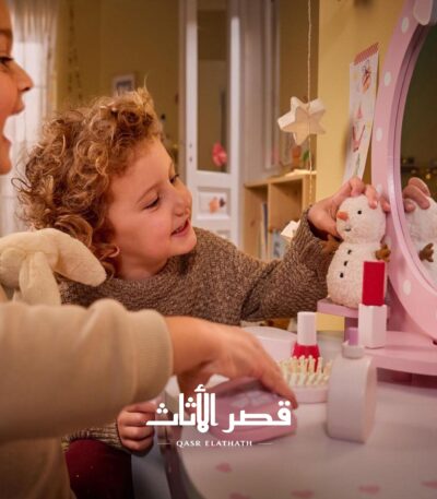 طفلان يستخدمان طاولة التجميل وأدوات اللعب الخشبية